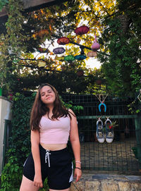 Portrait of young woman standing against tree