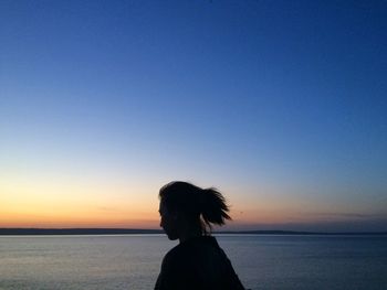 Silhouette woman by sea against clear sky during sunset