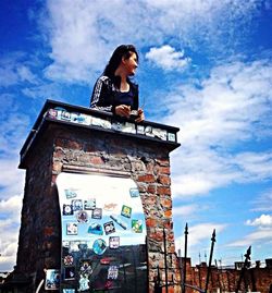 Low angle view of young woman standing against sky