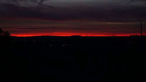 Silhouette landscape against dramatic sky during sunset