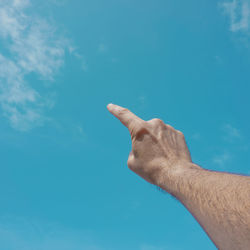 Cropped hand gesturing against sky