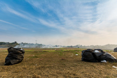 Garbage bags on field against sky