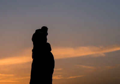 Silhouette man standing against orange sky