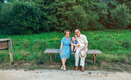 Full length of young couple on bench against trees