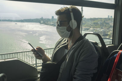 Rear view of man using mobile phone in bus