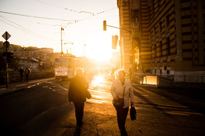 People walking on road in city at sunset