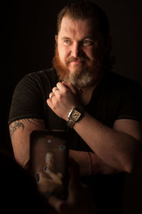 Portrait of man making face against black background