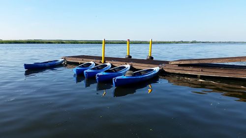 Boats moored in sea against clear blue sky