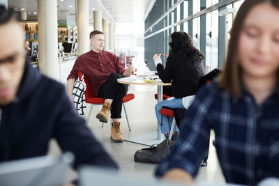 Friends talking while studying together at table in university cafeteria