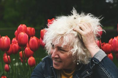 Portrait of smiling woman with red flowering plants