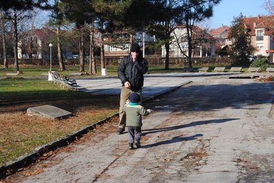 Rear view of man walking on footpath in city