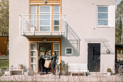 Female customer receiving package from young delivery woman