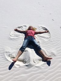 Full length of girl lying down at sandy beach on sunny day