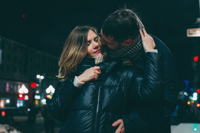 Young couple kissing in city at night