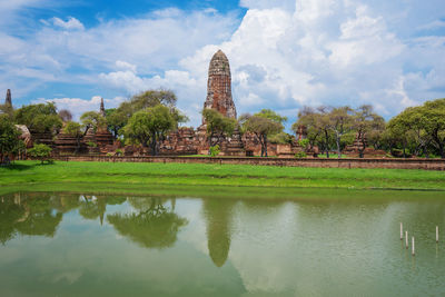 Reflection of temple and building on water against sky