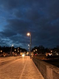 Empty road along illuminated street lights at night