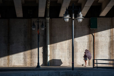 Rear view of woman walking on street against building