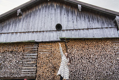 A young lady throwing her hat into the air by a wooden barn