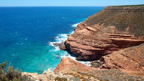 Rock formations by sea against blue sky