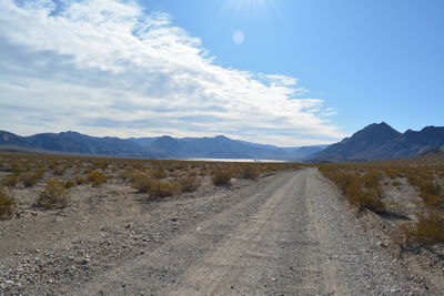 Dirt road by mountains against sky - race track playa death valley national park