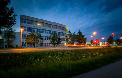 Illuminated street light by road against sky at night