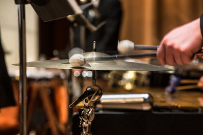 Close-up of hand holding drumsticks on cymbal