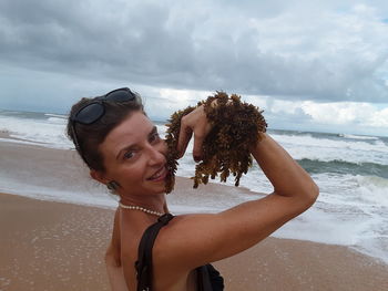 Portrait of beautiful woman on beach against sky