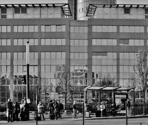 People walking on modern glass building in city