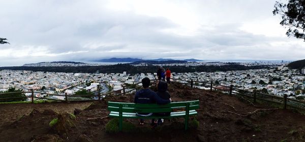 Man sitting on landscape against cloudy sky