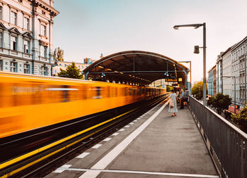 Train at railroad station in city against sky