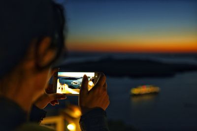 Close-up of woman photographing sea during sunset