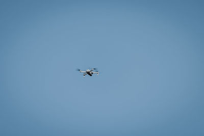 Drone flying in sky against blue background for copy space.