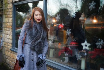 Portrait of smiling woman standing outside store during christmas