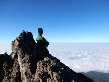 Hiker standing on peak looking at cloudscape