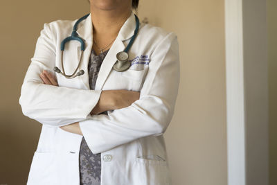 Midsection of female doctor with arms crossed standing in hospital