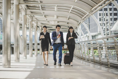 Full length of business people walking in office corridor