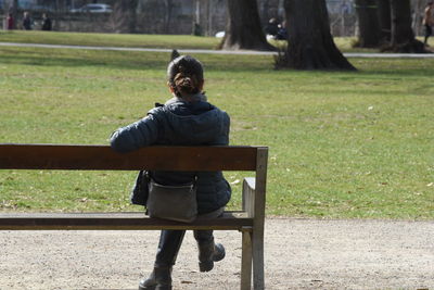 Rear view of man sitting on bench in park