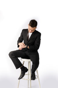 Young man sitting on chair against white background
