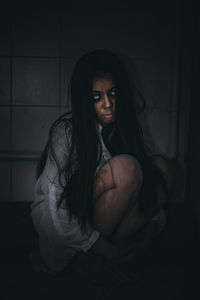 Portrait of beautiful woman sitting in the dark