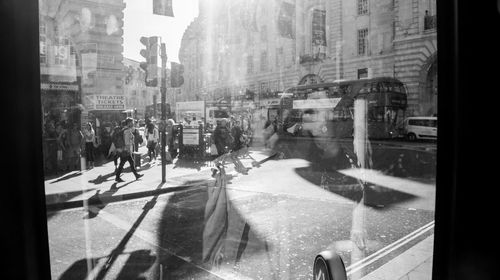 People walking on city street seen through glass window