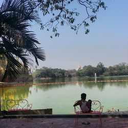 People sitting on bench by lake