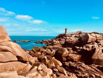 Rock formations on beach against blue sky