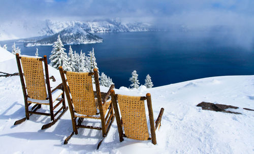 Chairs and table on snowcapped mountain by sea