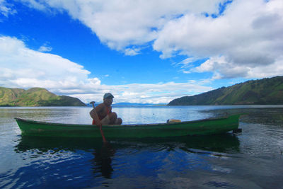 Man in boat on sea against sky