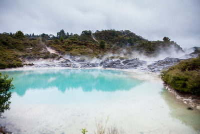 Scenic view of hot spring against cloudy sky