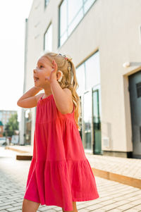 Side view of young woman standing against wall