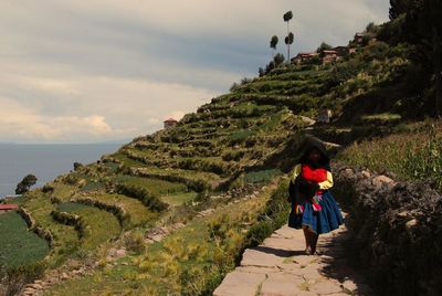 Rear view of woman walking on mountain against sky