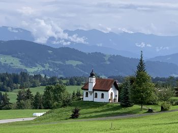 Curch on field by mountains against sky