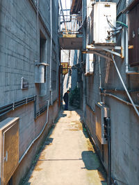 Rear view of woman walking on footpath amidst buildings