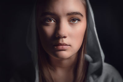 Close-up portrait of beautiful woman against black background